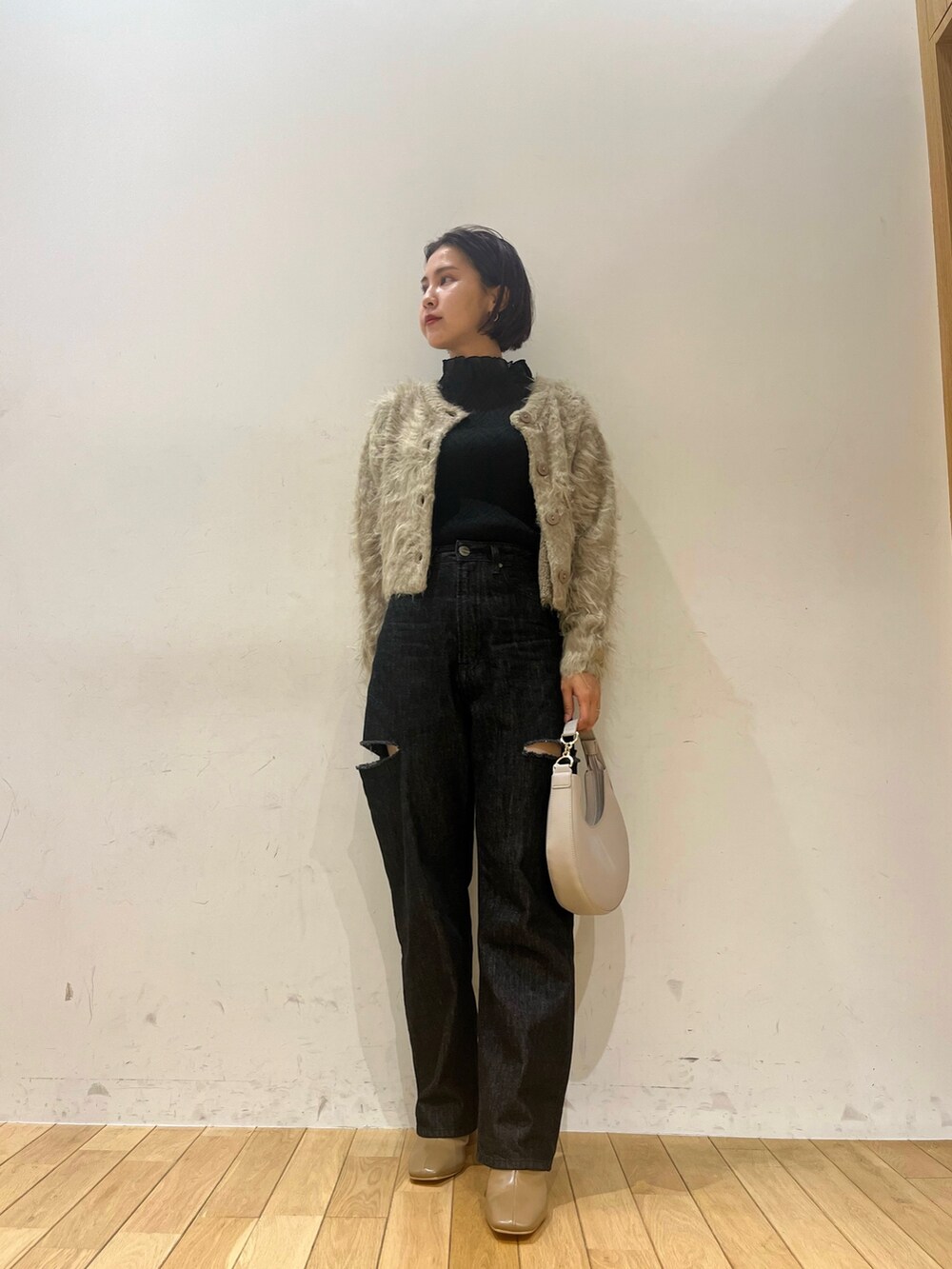 ホワイト系のハンドバッグ、ブラック系のデニムパンツ、ベージュ系のブーツを着用したレディースの秋コーディネートの3枚目の写真