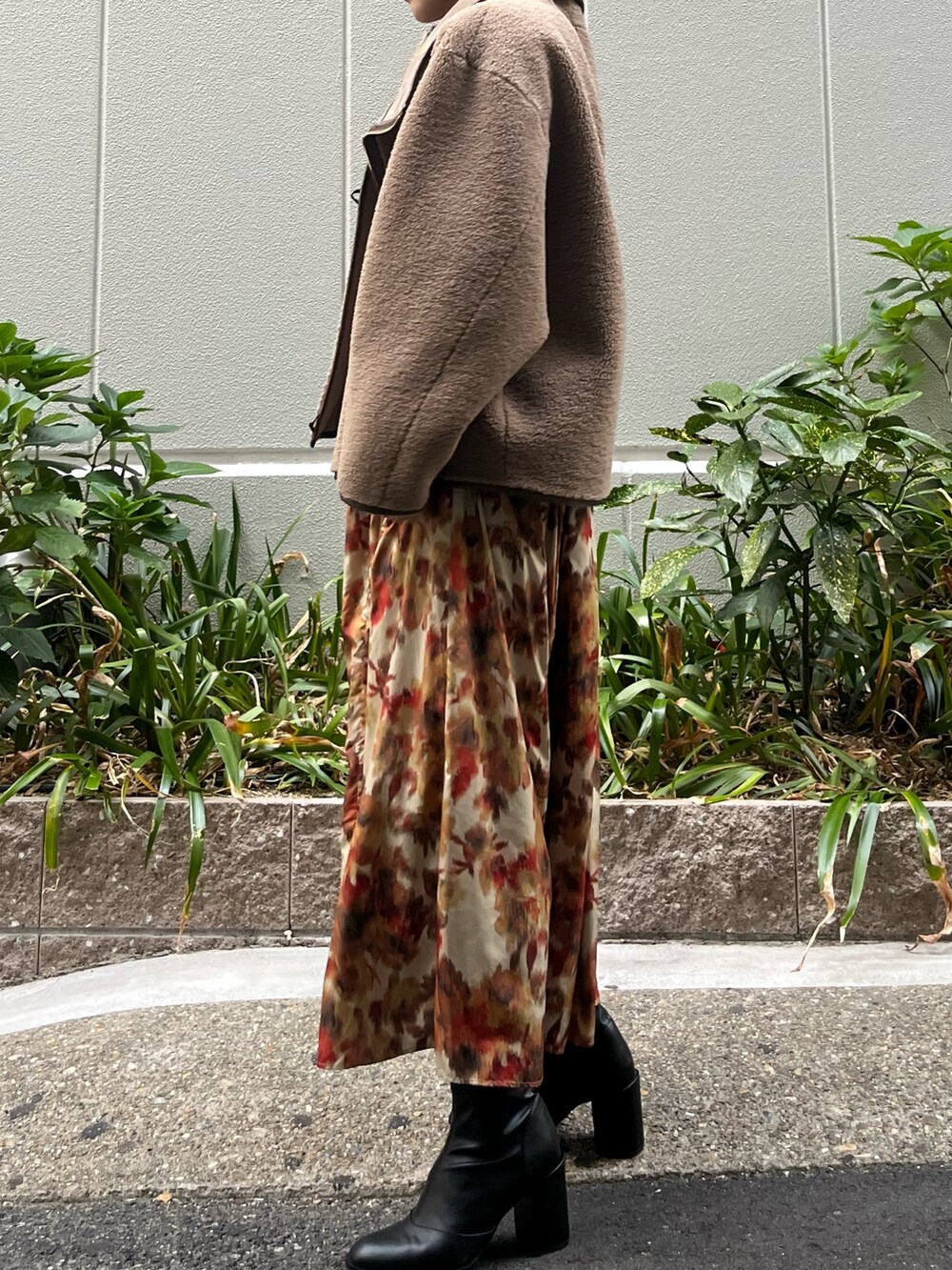 オレンジ系のスカート、ベージュ系のムートンコート、ブラック系のニット/セーターを着用したレディースの秋コーディネートの6枚目の写真