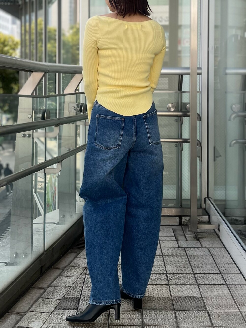 ブルー系のデニムパンツ、イエロー系のニット/セーター、ホワイト系のハンドバッグを着用したレディースの冬コーディネートの4枚目の写真