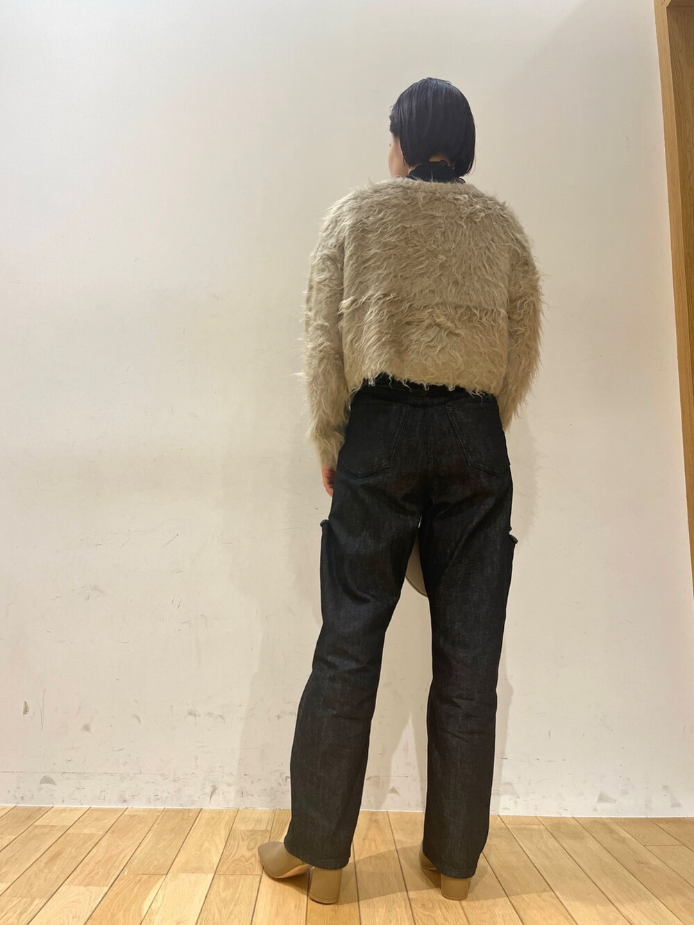 ホワイト系のハンドバッグ、ブラック系のデニムパンツ、ベージュ系のブーツを着用したレディースの秋コーディネートの4枚目の写真