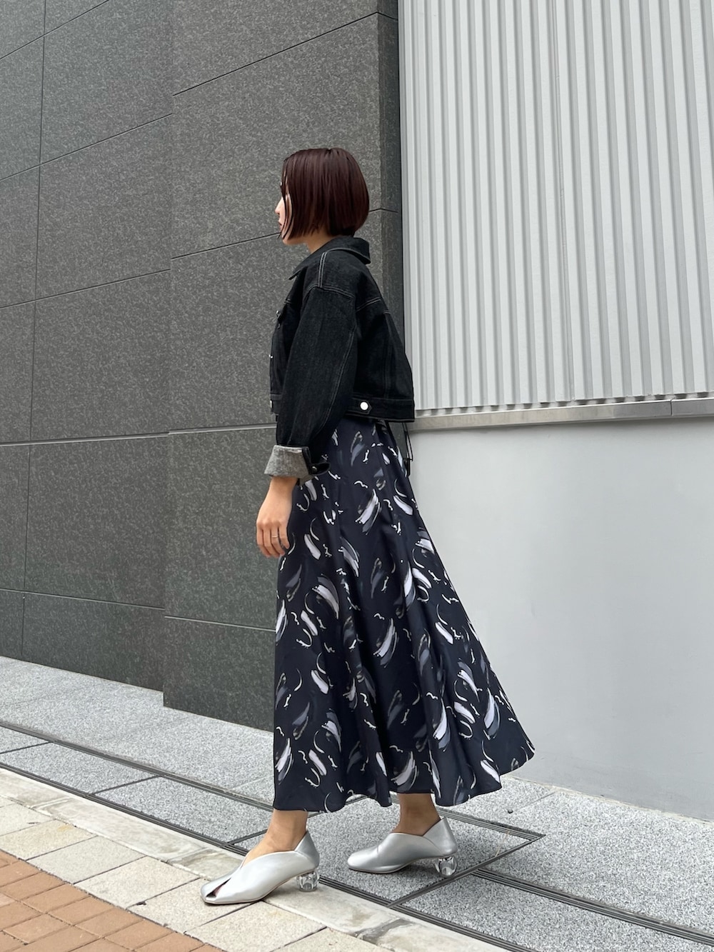 ブラック系のハンドバッグ、ブルー系のワンピース、シルバー系のパンプスを着用したレディースの春コーディネートの2枚目の写真