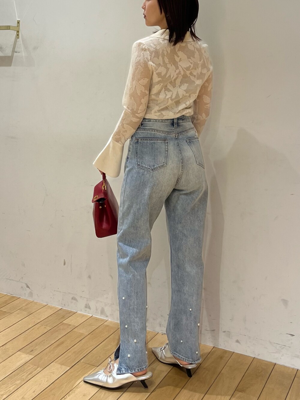 シルバー系のサンダル、ホワイト系のニット/セーター、ブルー系のデニムパンツを着用したレディースの春コーディネートの3枚目の写真