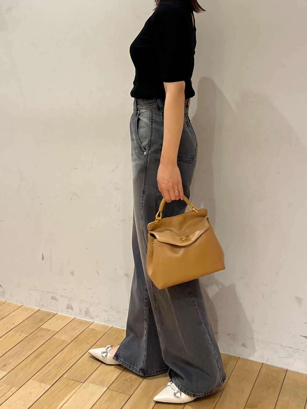 ブラック系のニット/セーター、ブラック系のデニムパンツ、ブラウン系のハンドバッグを着用したレディースの春コーディネートの2枚目の写真