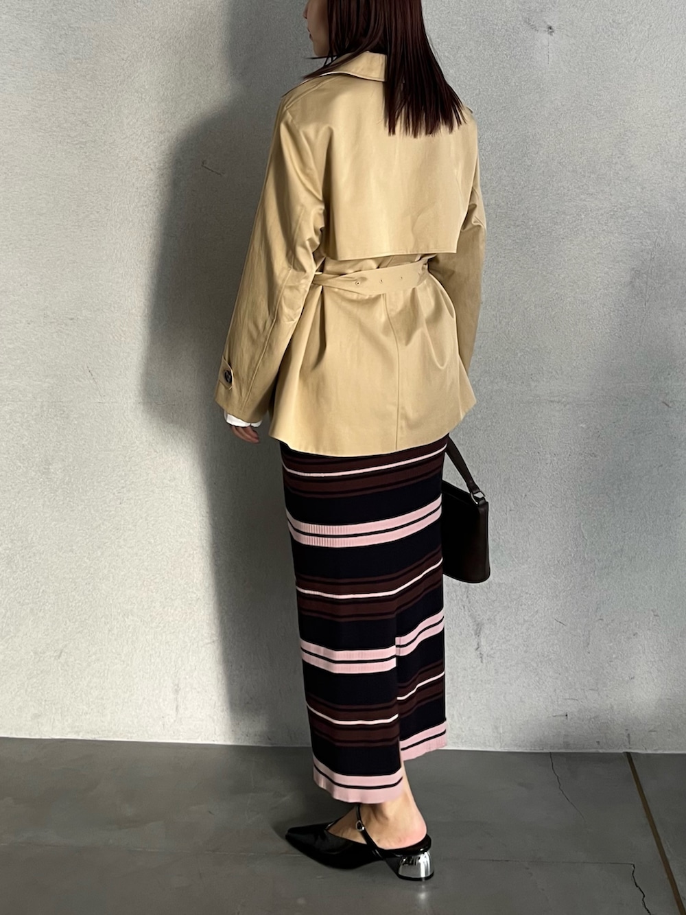 ブラウン系のハンドバッグ、ブラウン系のワンピース、ベージュ系のトレンチコートを着用したレディースの冬コーディネートの3枚目の写真