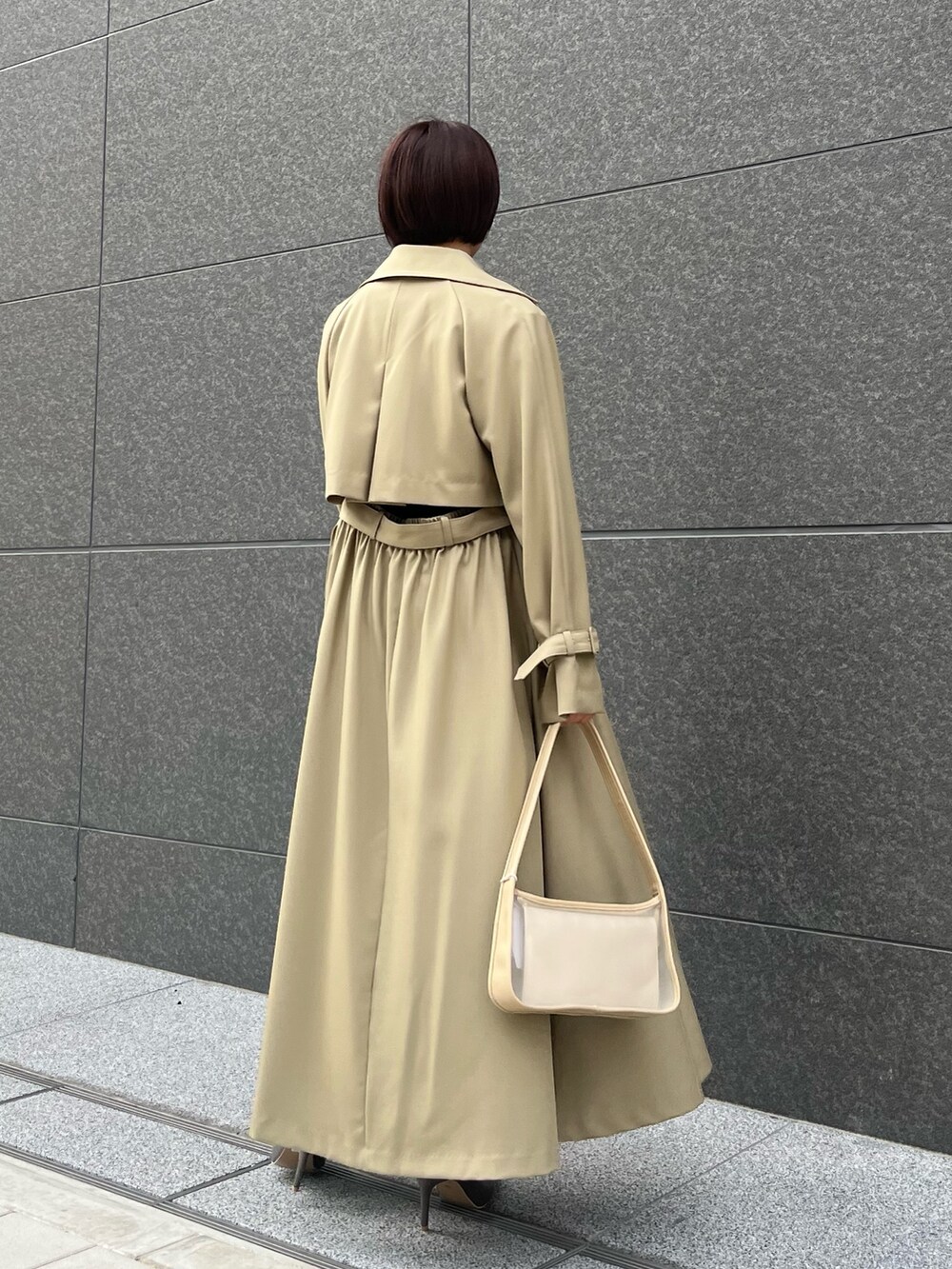 グリーン系のトレンチコート、シルバー系のパンプス、ブラック系のパンツドレスを着用したレディースの春コーディネートの4枚目の写真