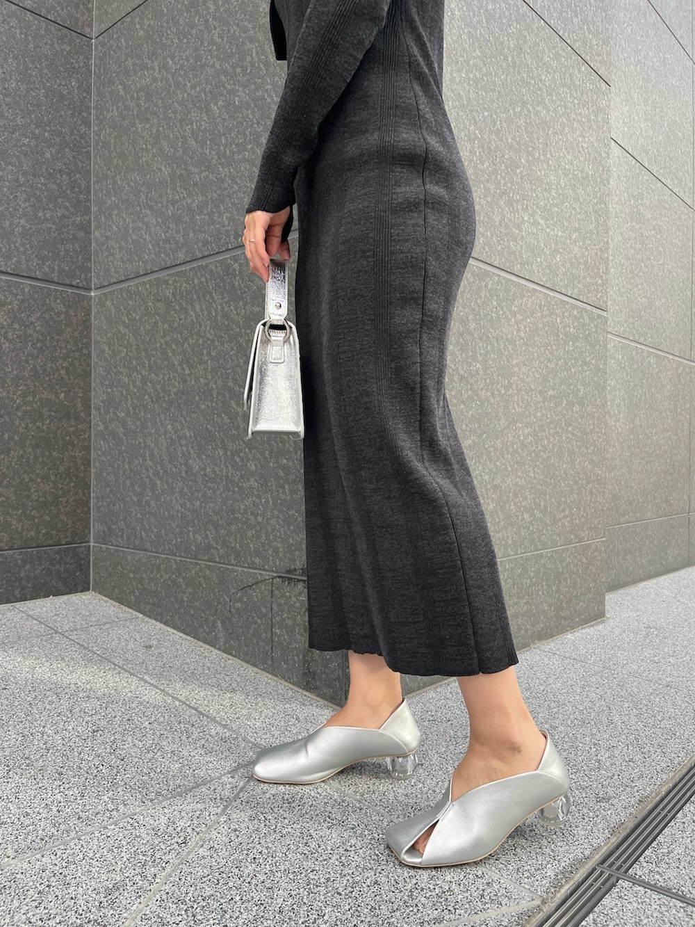 シルバー系のショルダーバッグ、シルバー系のパンプス、ブラック系のワンピースを着用したレディースの春コーディネートの7枚目の写真