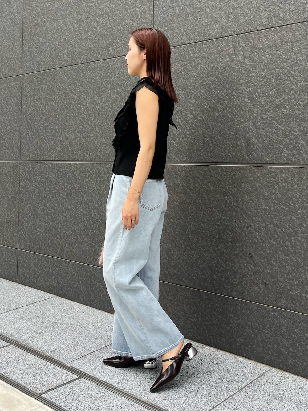 ブラック系のニット/セーター、ブルー系のデニムパンツ、ベージュ系のボストンバッグを着用したレディースの夏コーディネートの2枚目の写真