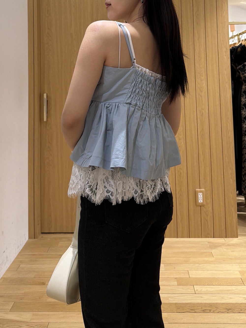 ブラック系のデニムパンツ、ホワイト系のハンドバッグ、ブルー系のキャミソールを着用したレディースの夏コーディネートの5枚目の写真