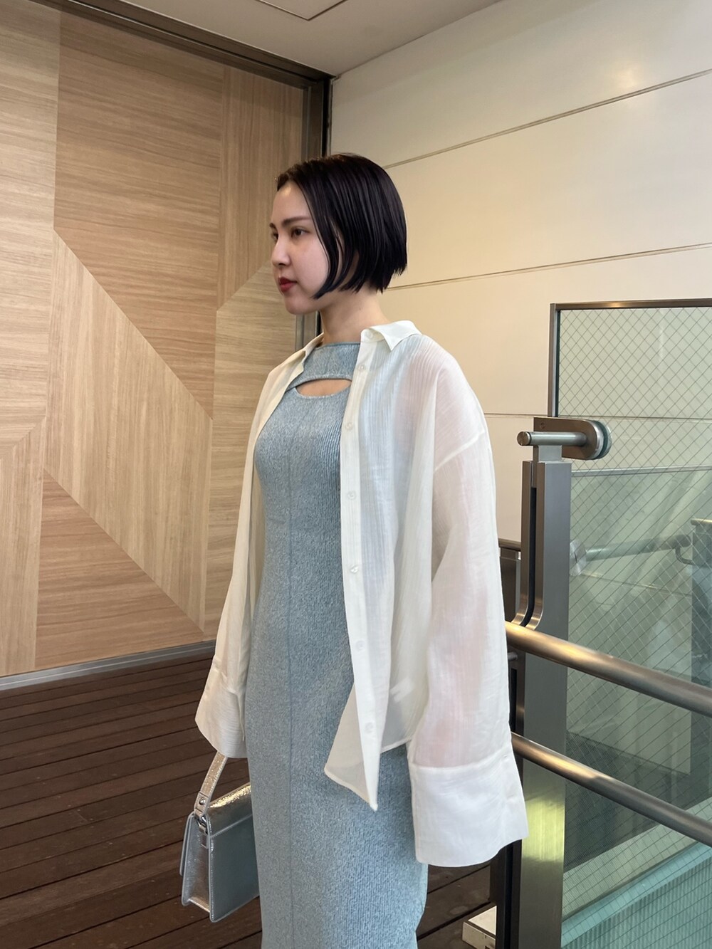 シルバー系のショルダーバッグ、ホワイト系のスニーカー、ブルー系のワンピースを着用したレディースの春コーディネートの5枚目の写真