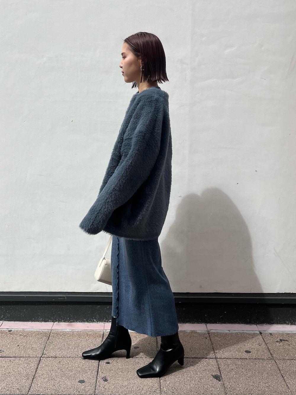 ブラック系のブーツ、ホワイト系のショルダーバッグ、ブルー系のワンピースを着用したレディースの秋コーディネートの2枚目の写真