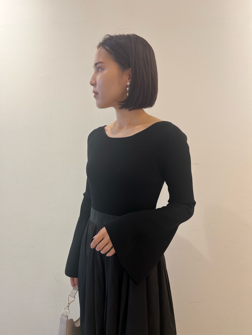 ブラック系のワンピース、ホワイト系のハンドバッグ、ブラック系のパンプスを着用したレディースの秋コーディネートの5枚目の写真