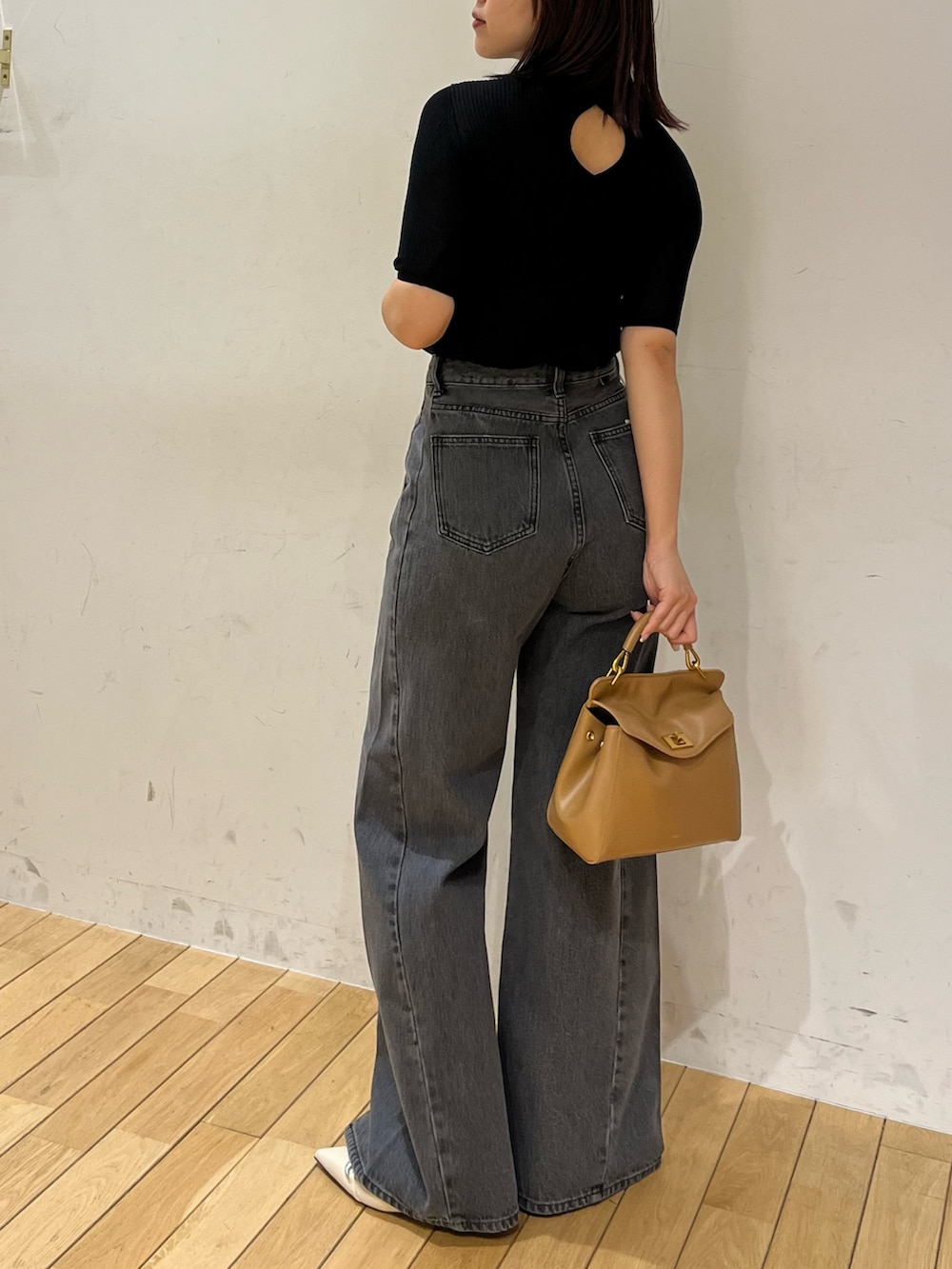 ブラック系のニット/セーター、ブラック系のデニムパンツ、ブラウン系のハンドバッグを着用したレディースの春コーディネートの3枚目の写真
