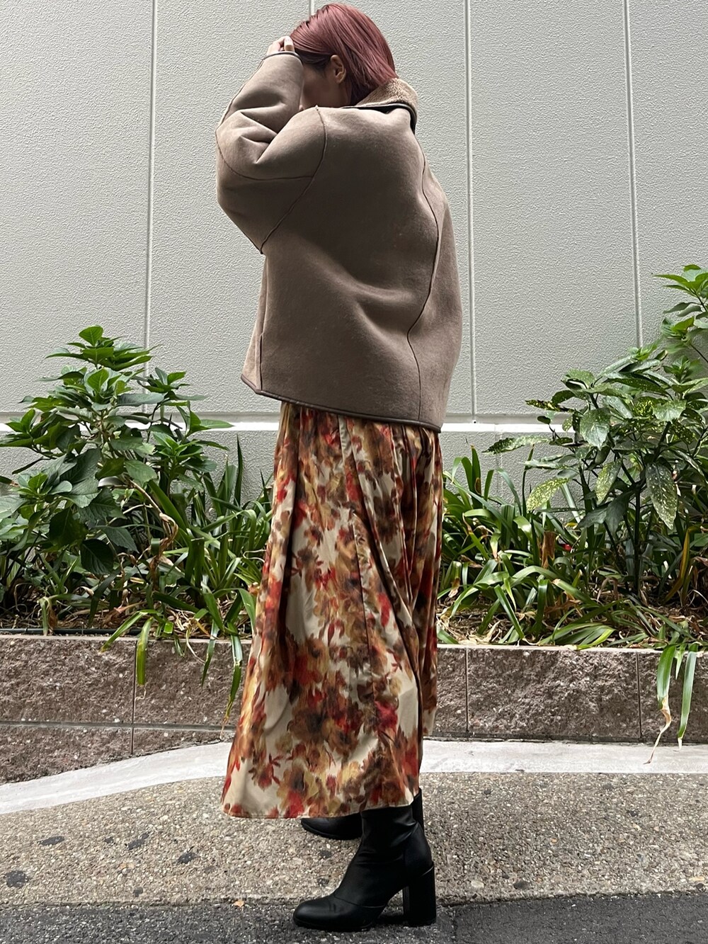 オレンジ系のスカート、ベージュ系のムートンコート、ブラック系のニット/セーターを着用したレディースの秋コーディネートの2枚目の写真