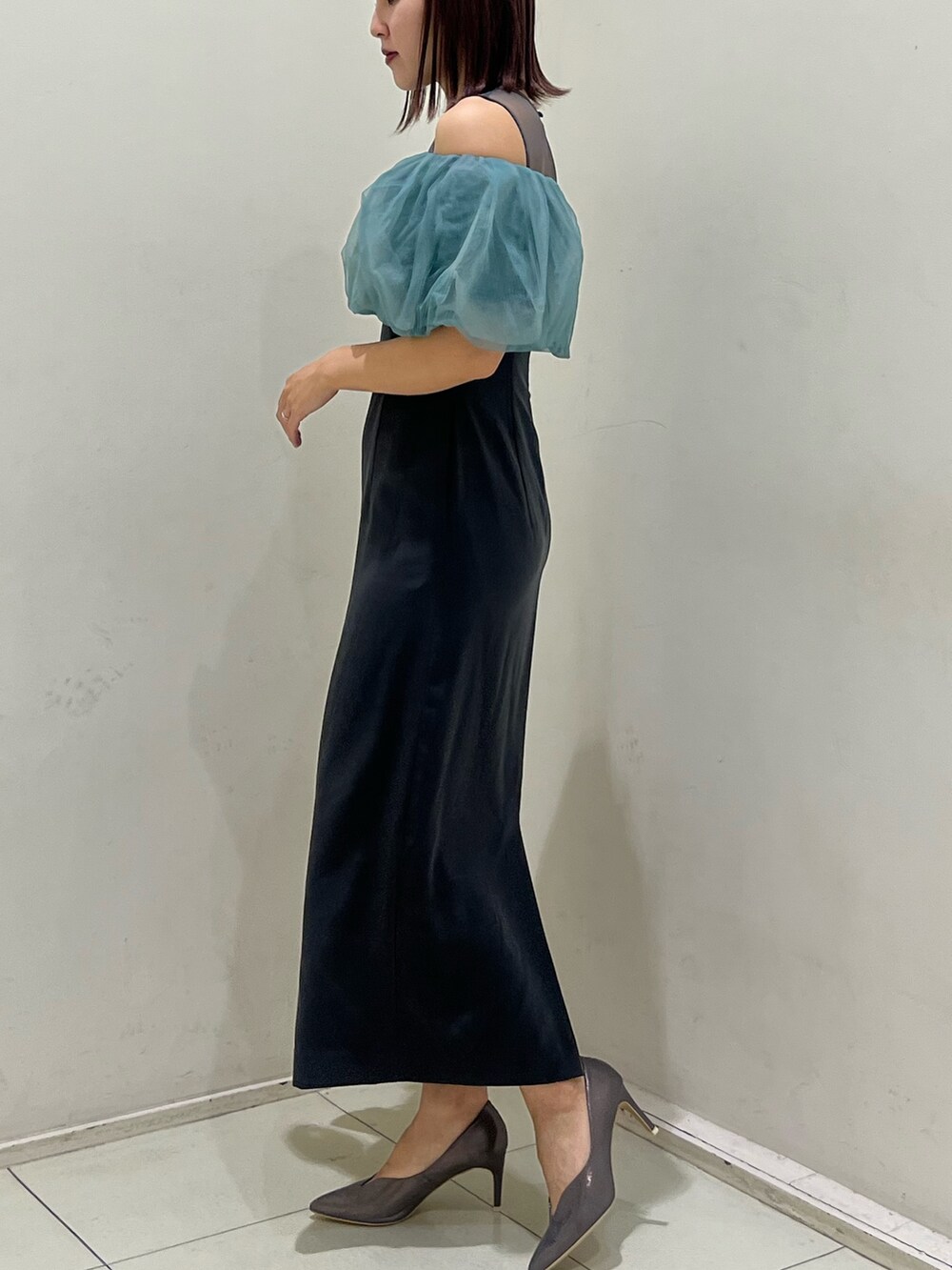 シルバー系のクラッチバッグ、シルバー系のパンプス、グレー系のドレスを着用したレディースの冬コーディネートの2枚目の写真