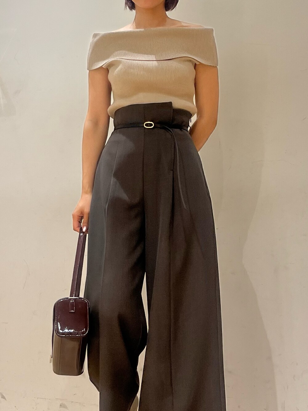 レッド系のショルダーバッグ、ベージュ系のニット/セーター、シルバー系のブーツを着用したレディースの秋コーディネートの4枚目の写真