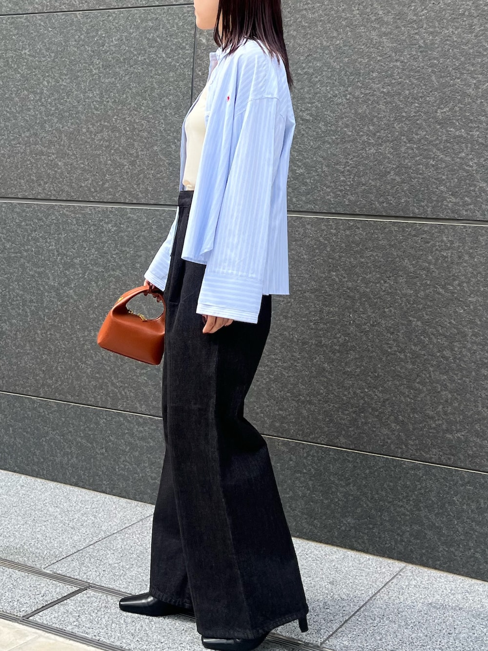 ブラック系のブーツ、ブラック系のデニムパンツ、レッド系のハンドバッグを着用したレディースの秋コーディネートの2枚目の写真