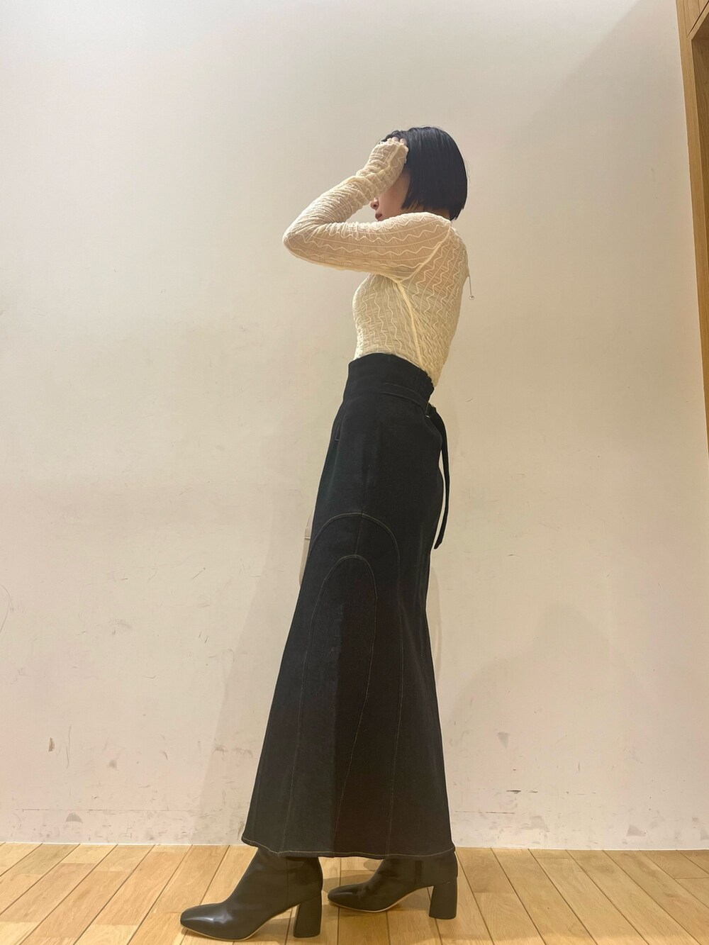 ブラック系のハンドバッグ、ブラック系のデニムスカート、ブラック系のブーツを着用したレディースの秋コーディネートの4枚目の写真