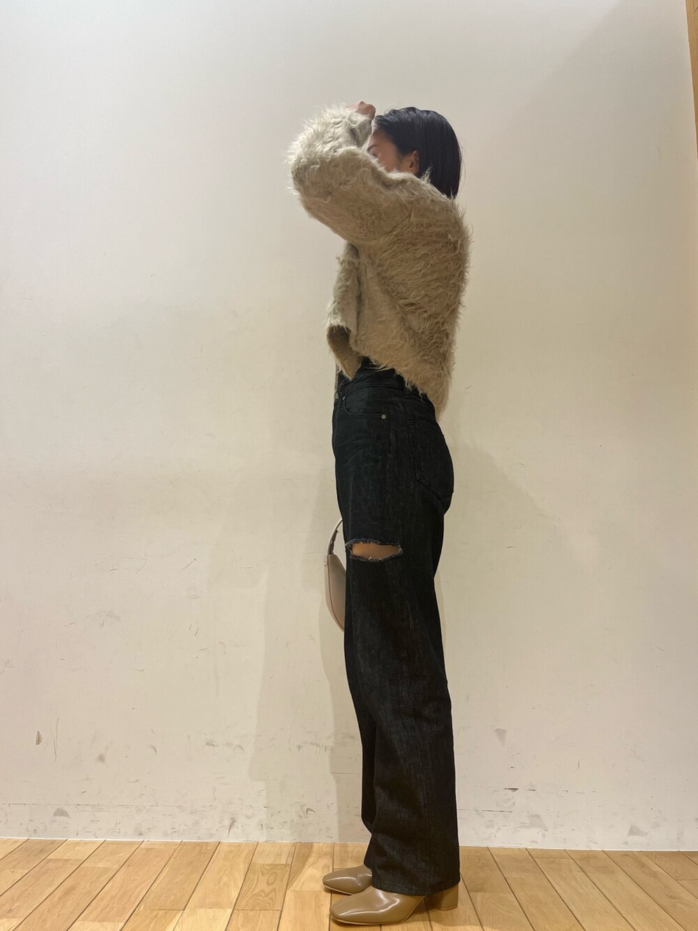 ホワイト系のハンドバッグ、ブラック系のデニムパンツ、ベージュ系のブーツを着用したレディースの秋コーディネートの6枚目の写真