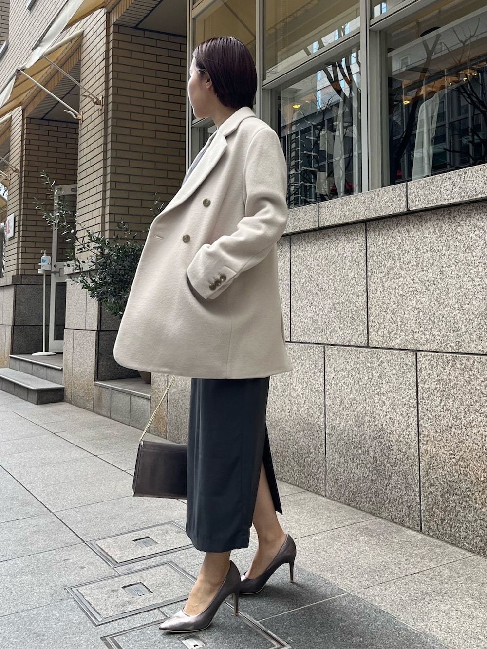 グレー系のドレス、シルバー系のパンプス、シルバー系のハンドバッグを着用したレディースの冬コーディネートの5枚目の写真