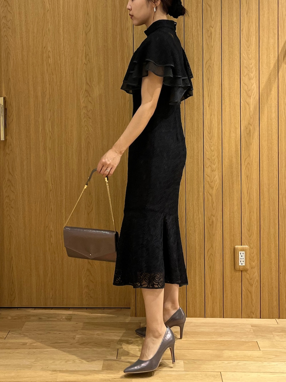 ブラック系のドレス、シルバー系のパンプス、シルバー系のクラッチバッグを着用したレディースの秋コーディネートの2枚目の写真