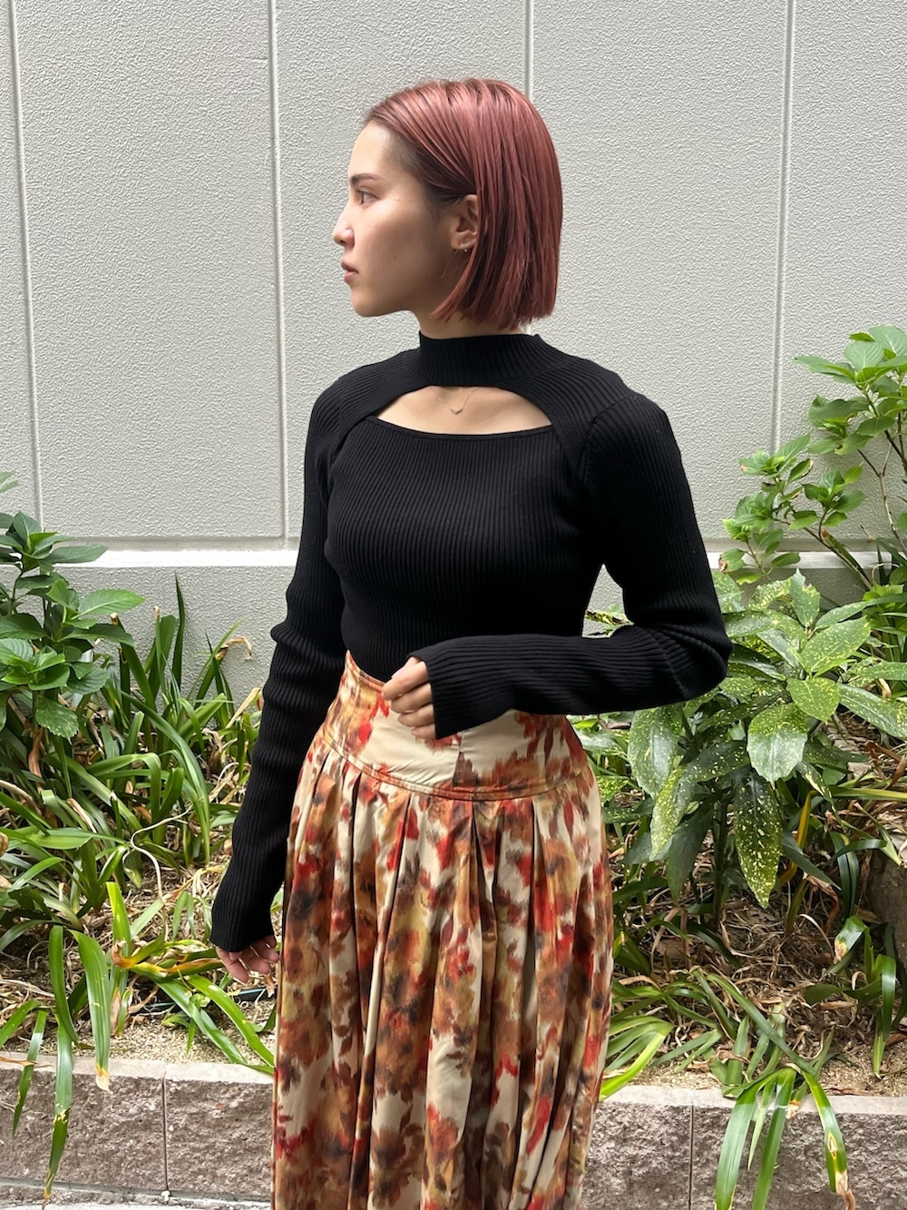 オレンジ系のスカート、ブラック系のニット/セーター、ベージュ系のムートンコートを着用したレディースの秋コーディネートの2枚目の写真