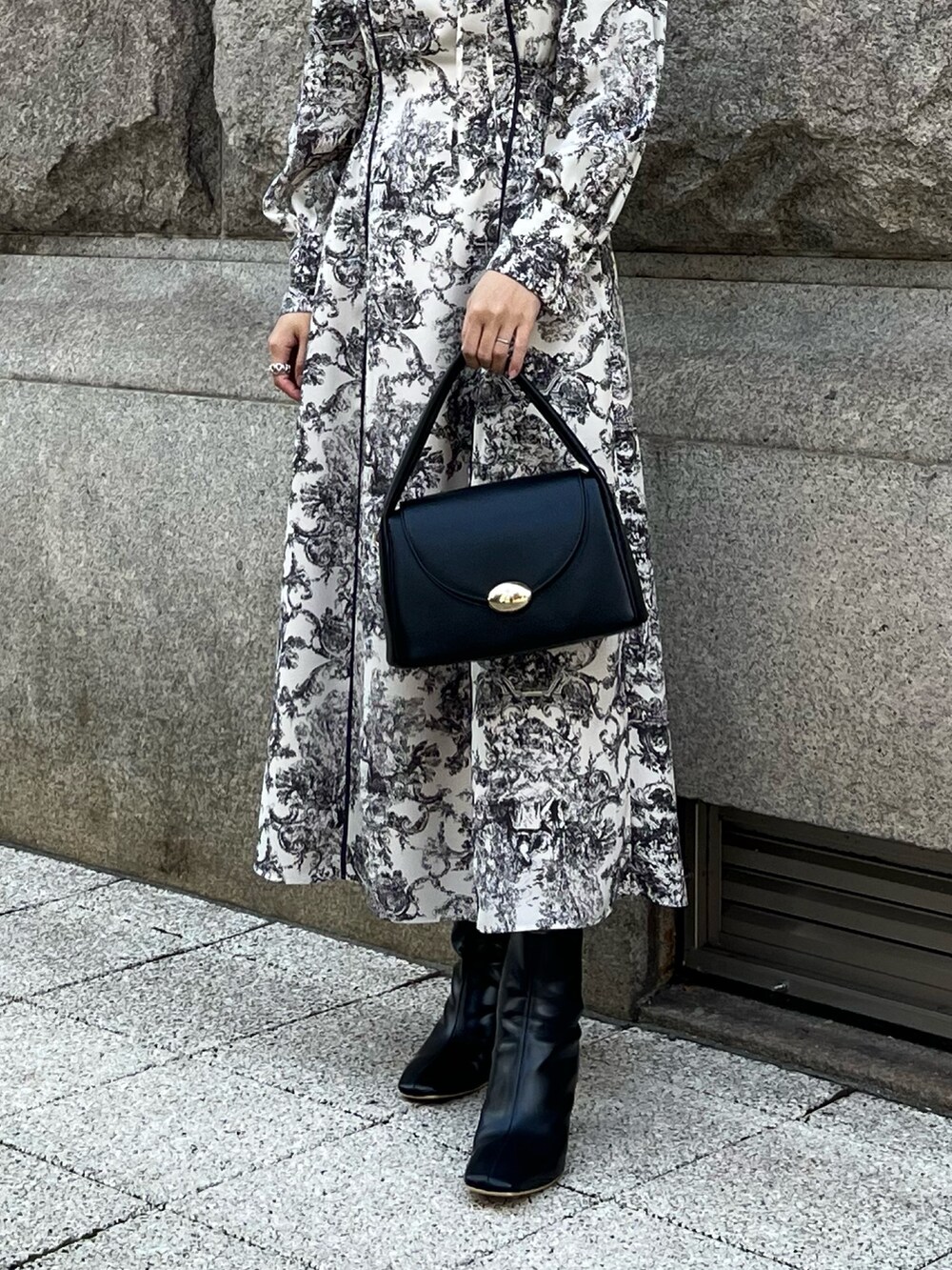 ホワイト系のワンピース、ブラック系のハンドバッグ、ブラック系のブーツを着用したレディースの冬コーディネートの7枚目の写真