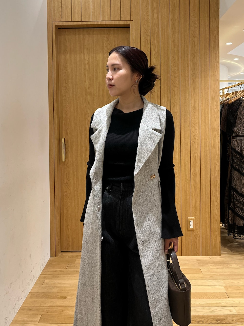 ブラウン系のハンドバッグ、ブラック系のデニムパンツ、グレー系のワンピースを着用したレディースの秋コーディネートの4枚目の写真