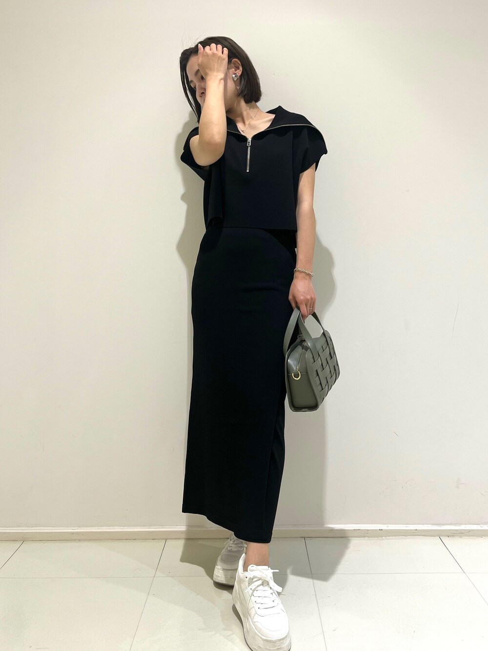 ブラック系のスカート、ブラック系のニット/セーター、グリーン系のショルダーバッグを着用したレディースの春コーディネートの2枚目の写真