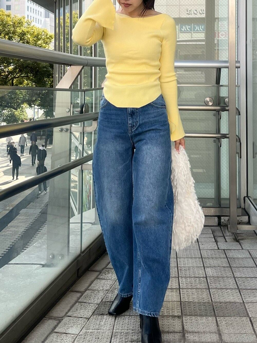 ブルー系のデニムパンツ、イエロー系のニット/セーター、ホワイト系のハンドバッグを着用したレディースの冬コーディネートの2枚目の写真