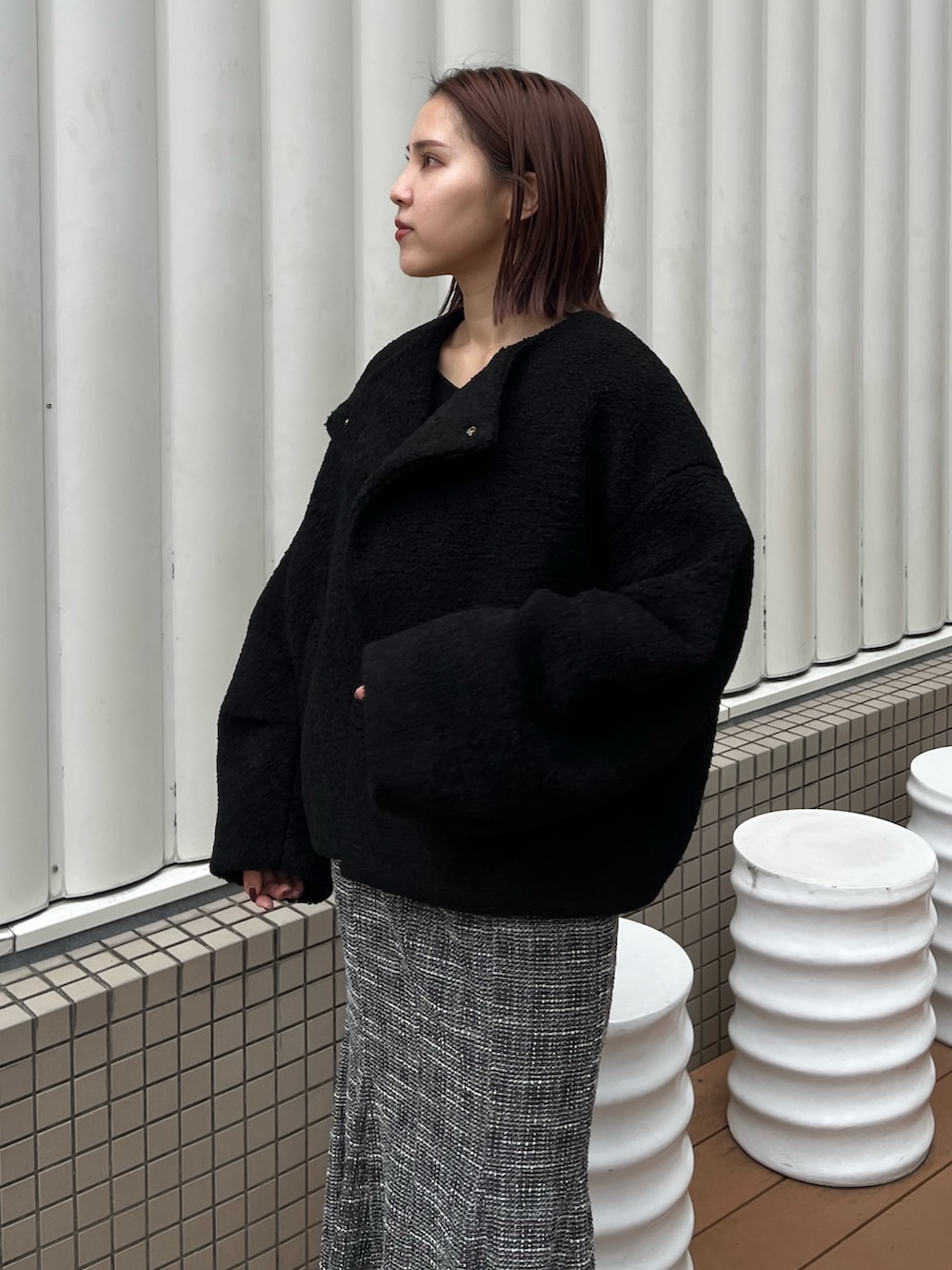 ブラック系のブルゾン、ブラック系のニット/セーター、ブラック系のスカートを着用したレディースの秋コーディネートの5枚目の写真