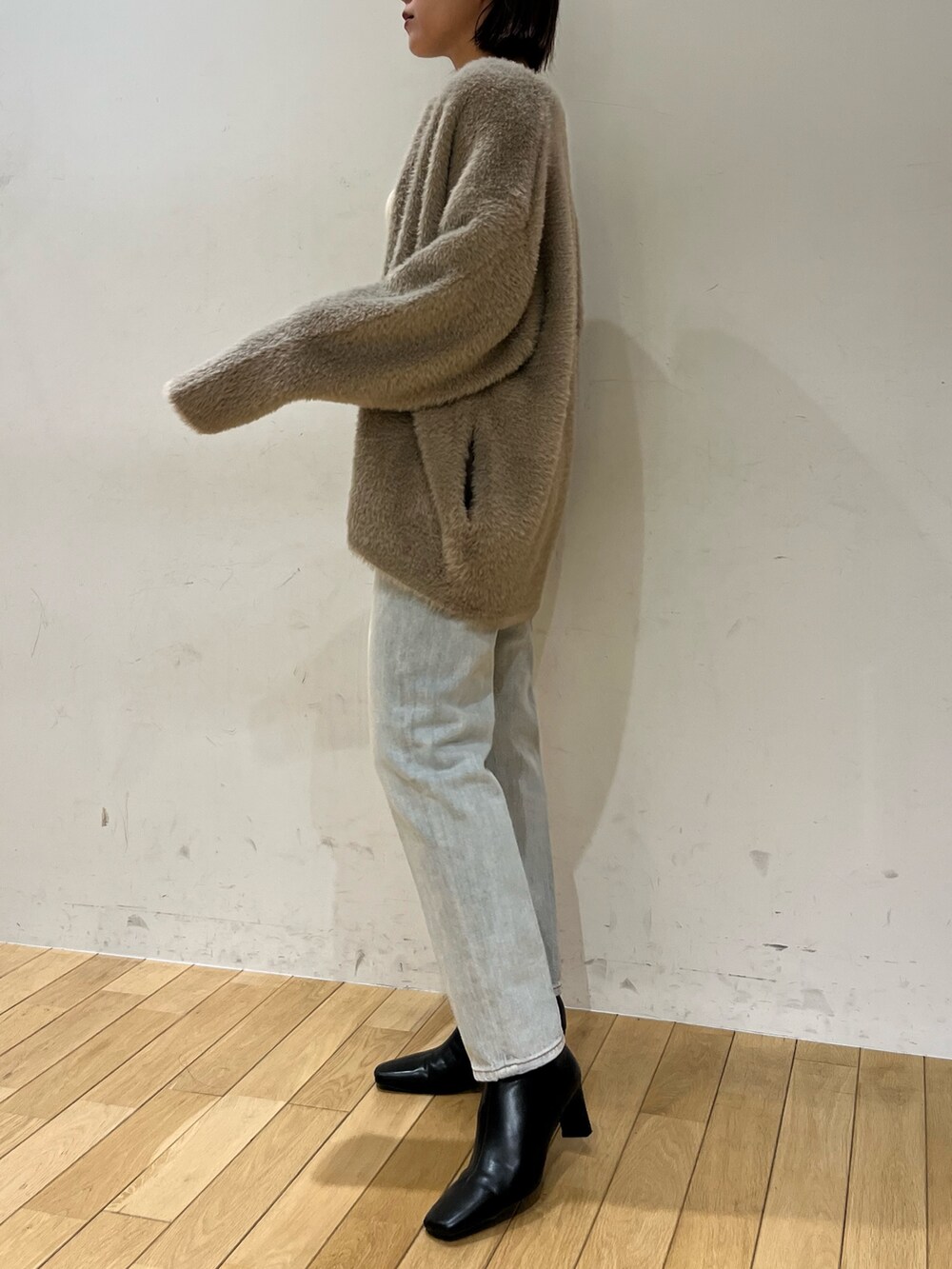 ブルー系のデニムパンツ、ホワイト系のニット/セーター、ブラウン系のカーディガン/ボレロを着用したレディースの秋コーディネートの2枚目の写真