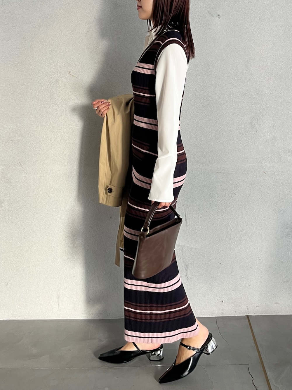 ブラウン系のハンドバッグ、ブラウン系のワンピース、ベージュ系のトレンチコートを着用したレディースの冬コーディネートの9枚目の写真