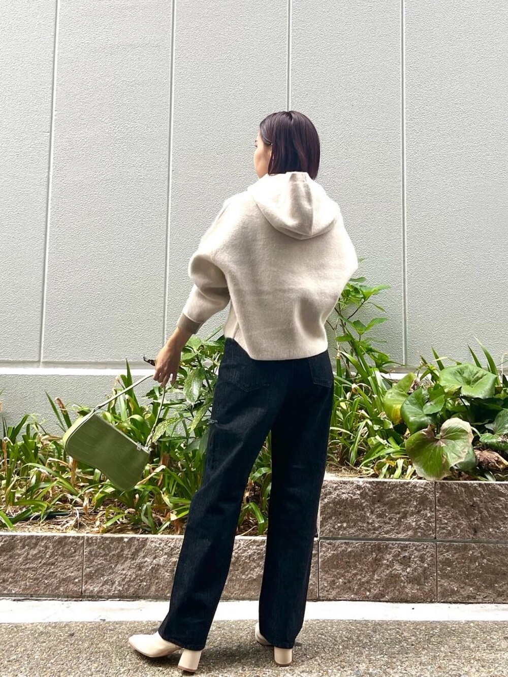 ホワイト系のブーツ、ブラック系のデニムパンツ、グリーン系のハンドバッグを着用したレディースの秋コーディネートの5枚目の写真