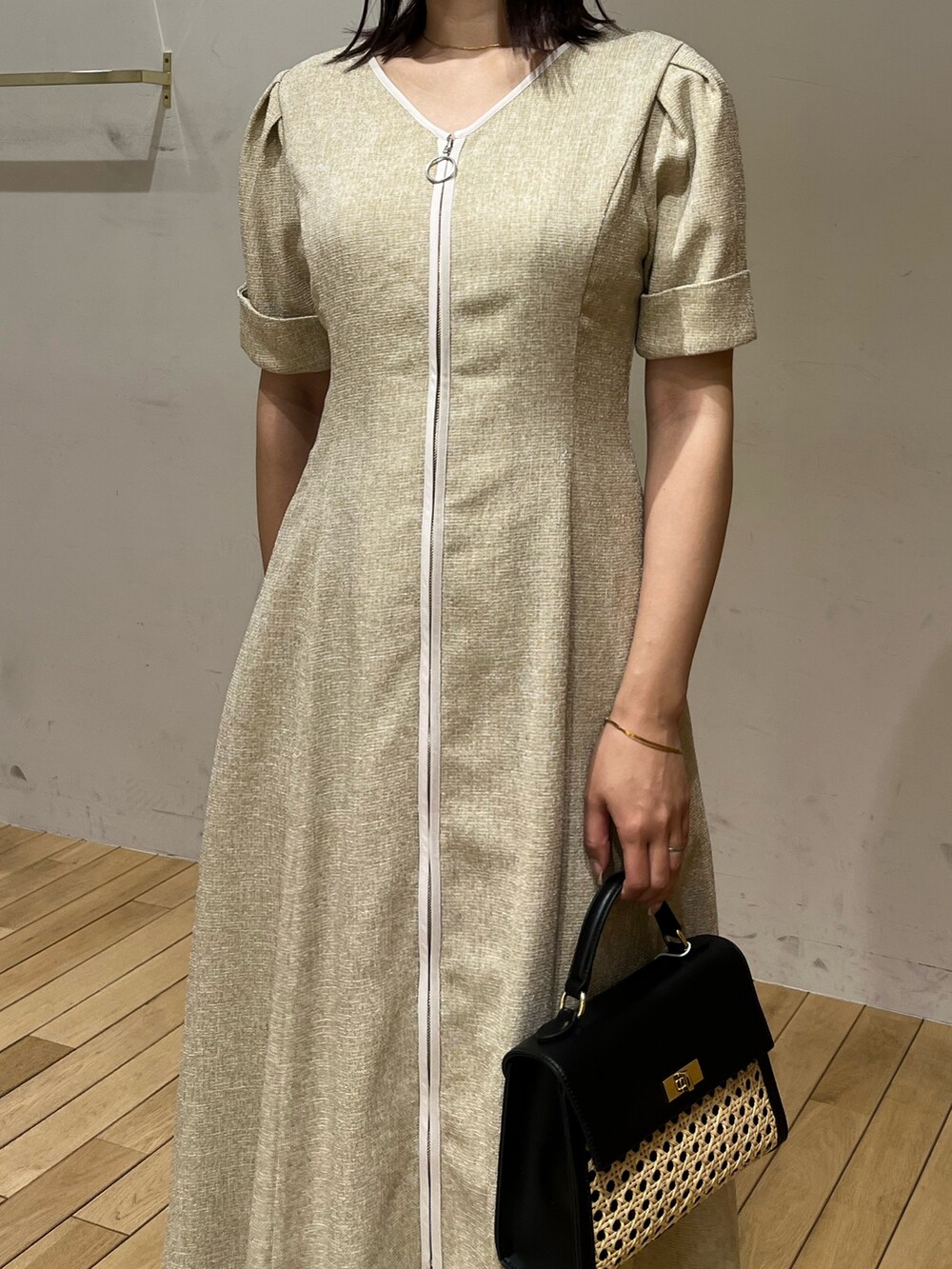 ベージュ系のワンピース、ホワイト系のサンダル、ブラック系のハンドバッグを着用したレディースの春コーディネートの5枚目の写真