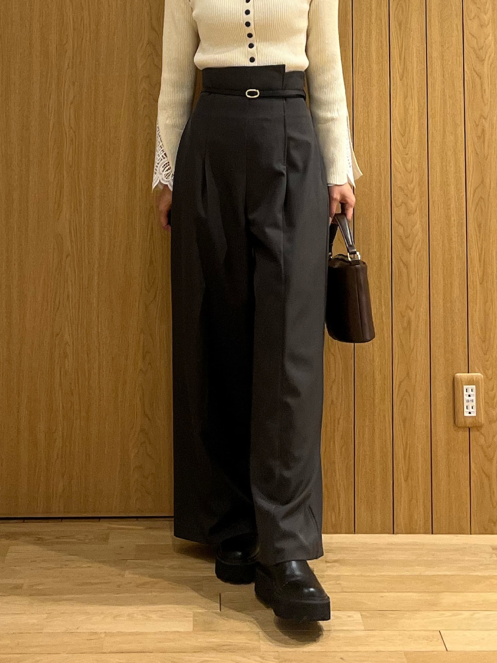 グレー系のその他パンツ、ホワイト系のニット/セーター、ブラウン系のハンドバッグを着用したレディースの冬コーディネートの6枚目の写真