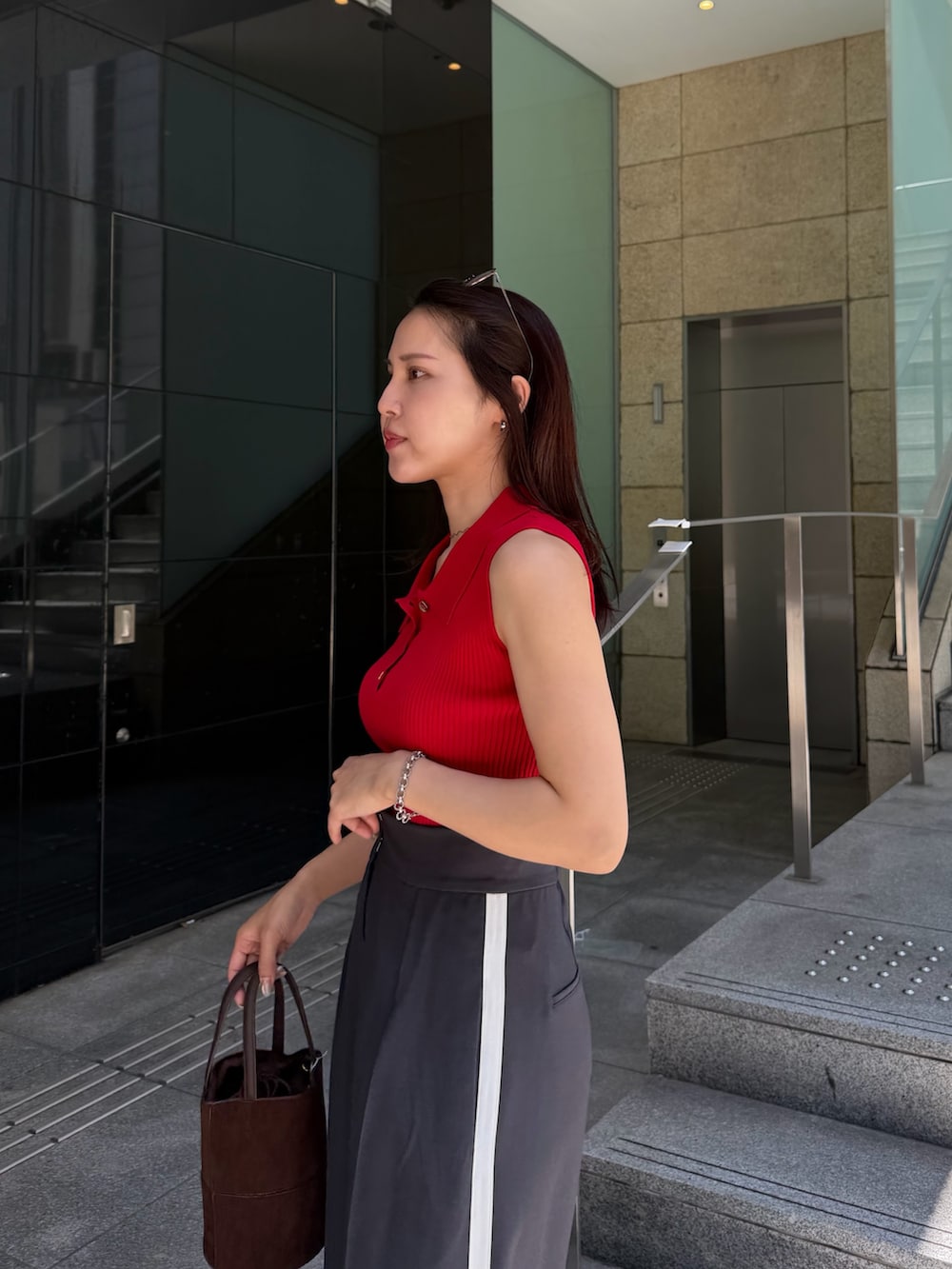 グレー系のその他パンツ、レッド系のニット/セーター、ブラウン系のハンドバッグを着用したレディースの春コーディネートの6枚目の写真