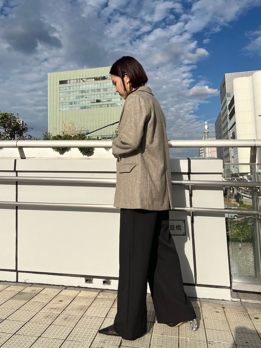 ブラック系のパンプス、シルバー系のハンドバッグ、グレー系のテーラードジャケットを着用したレディースの秋コーディネートの4枚目の写真