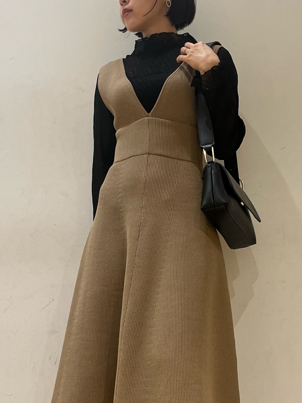 ブラック系のブーツ、ブラウン系のジャンパースカート、ブラック系のショルダーバッグを着用したレディースの秋コーディネートの4枚目の写真