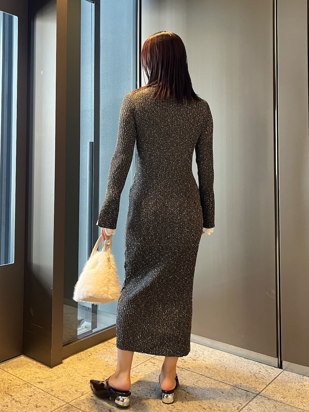 ホワイト系のボストンバッグ、ブラウン系のパンプス、グレー系のワンピースを着用したレディースの夏コーディネートの3枚目の写真