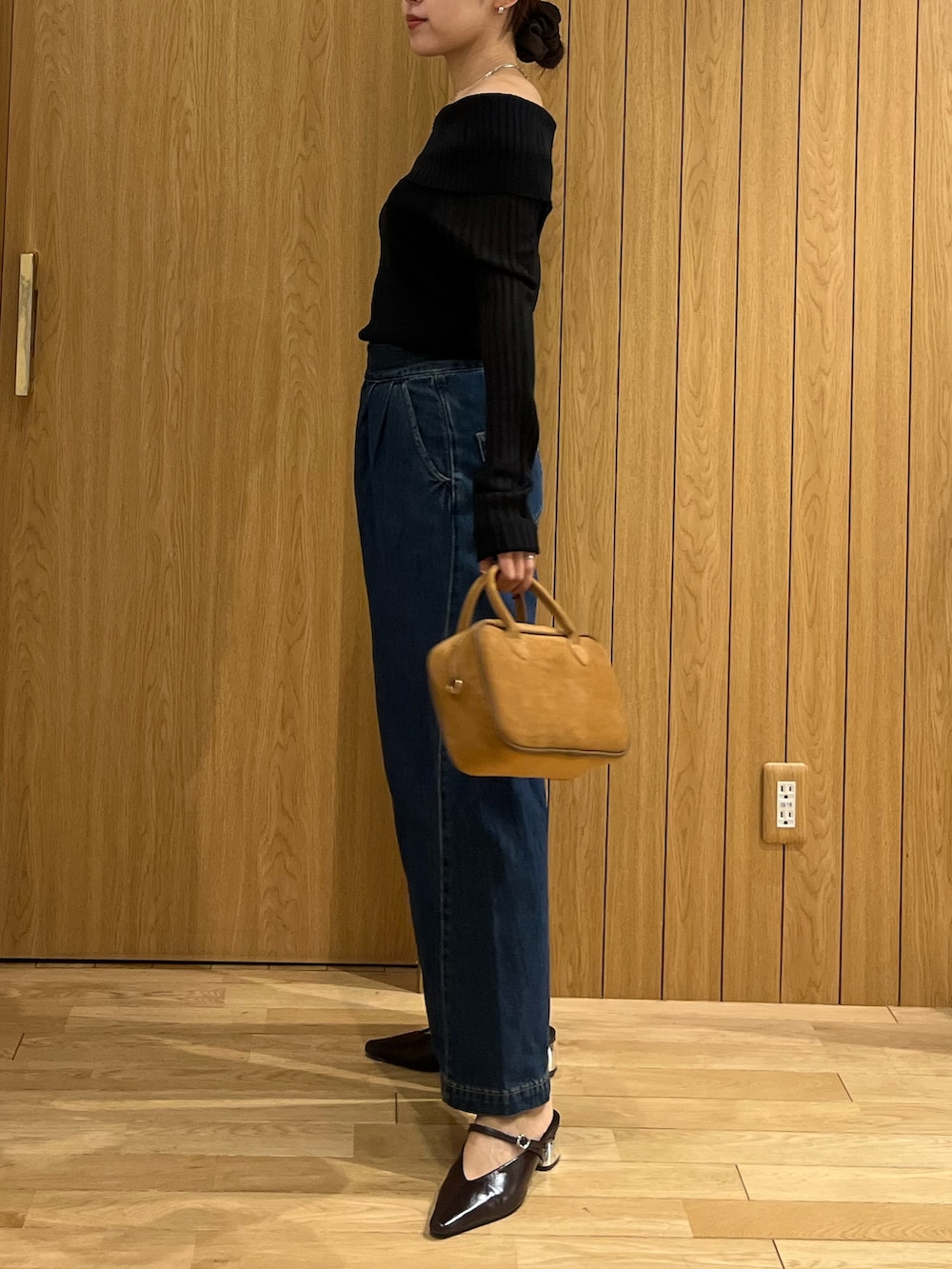 ブラウン系のパンプス、ブラウン系のハンドバッグ、ブルー系のデニムパンツを着用したレディースの秋コーディネートの2枚目の写真