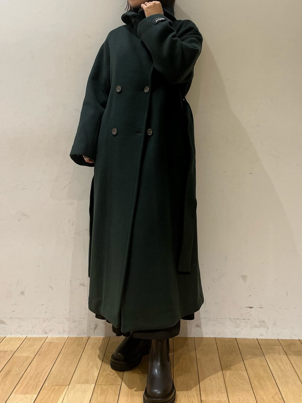 ブラック系のブーツ、グリーン系のニット/セーター、グリーン系のステンカラーコートを着用したレディースの冬コーディネートの7枚目の写真