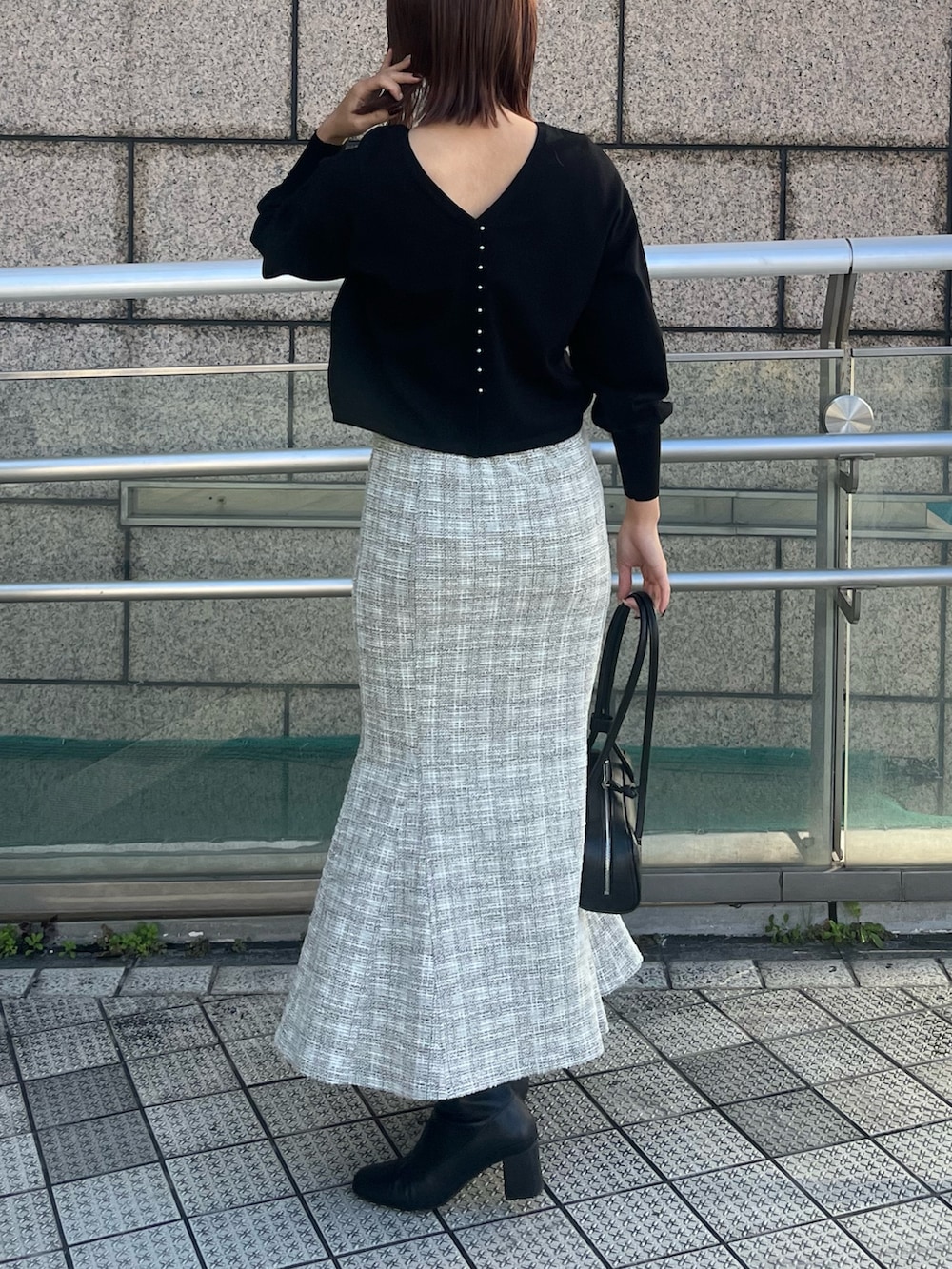 ホワイト系のスカート、ブラック系のニット/セーター、ブラック系のショルダーバッグを着用したレディースの冬コーディネートの3枚目の写真