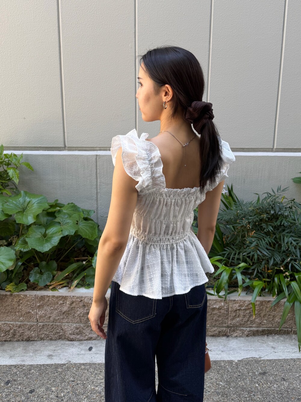 ブルー系のデニムパンツ、ブラウン系のハンドバッグ、ホワイト系のシャツ/ブラウスを着用したレディースの春コーディネートの6枚目の写真