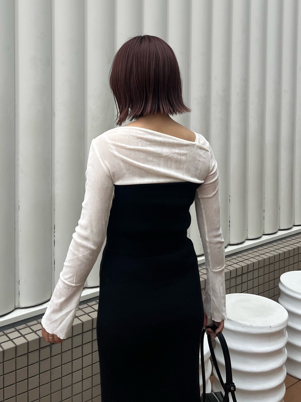 ブラック系のショルダーバッグ、ブラック系のワンピース、ホワイト系のTシャツ/カットソーを着用したレディースの秋コーディネートの6枚目の写真