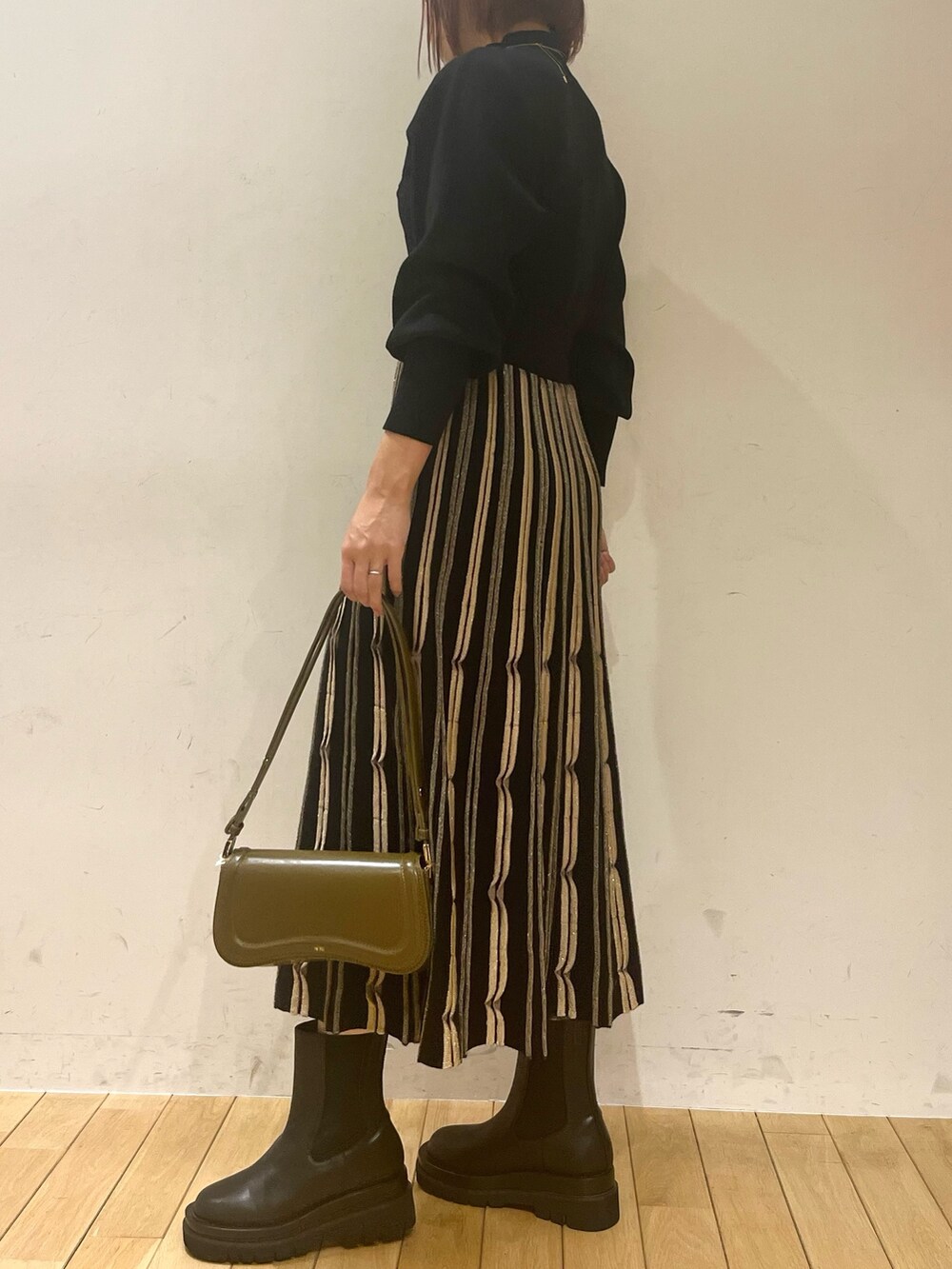 ブラック系のワンピース、ブラウン系のショルダーバッグ、ブラック系のダウンジャケット/コートを着用したレディースの秋コーディネートの6枚目の写真