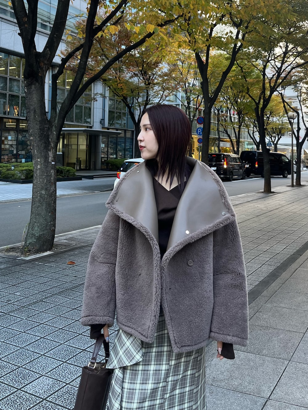 ベージュ系のムートンコート、ブラウン系のTシャツ/カットソー、ブラウン系のスカートを着用したレディースの冬コーディネートの8枚目の写真