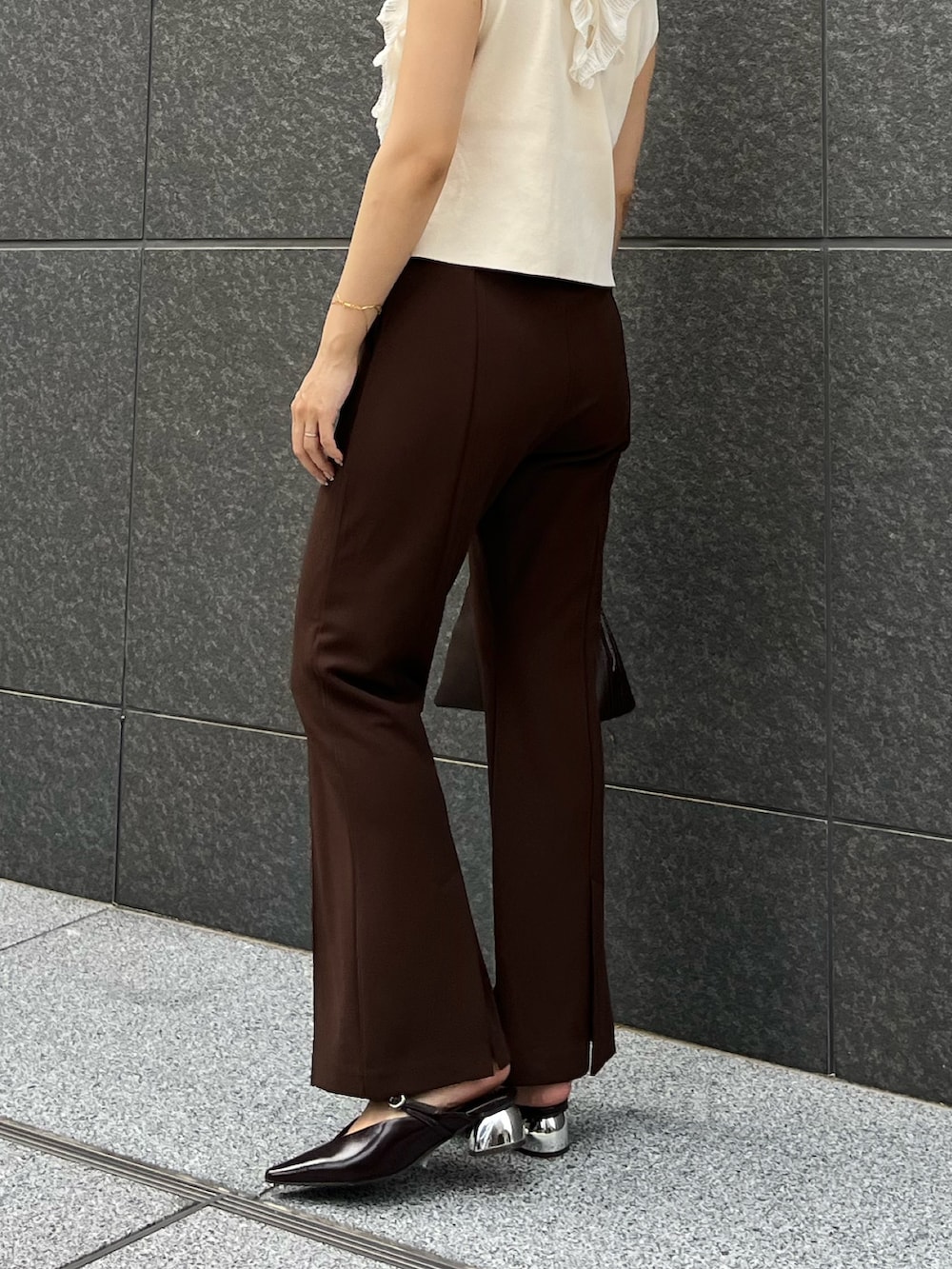 ホワイト系のニット/セーター、ブラウン系のその他パンツ、ブラウン系のボストンバッグを着用したレディースの夏コーディネートの4枚目の写真