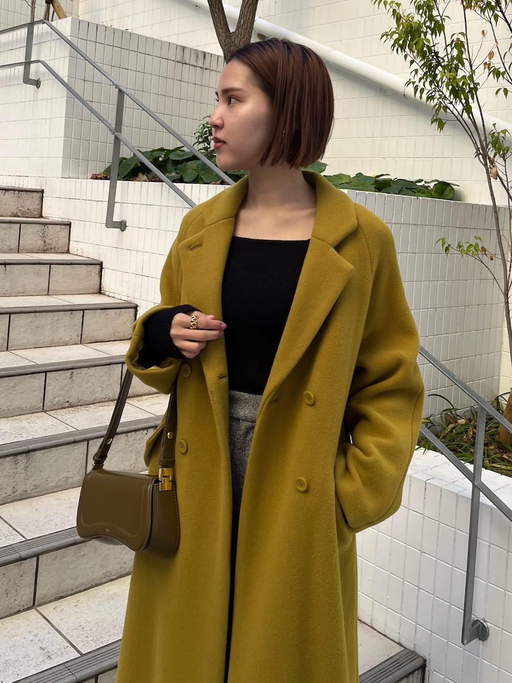 グリーン系のチェスターコート、ブラック系のその他パンツ、ブラック系のニット/セーターを着用したレディースの冬コーディネートの6枚目の写真