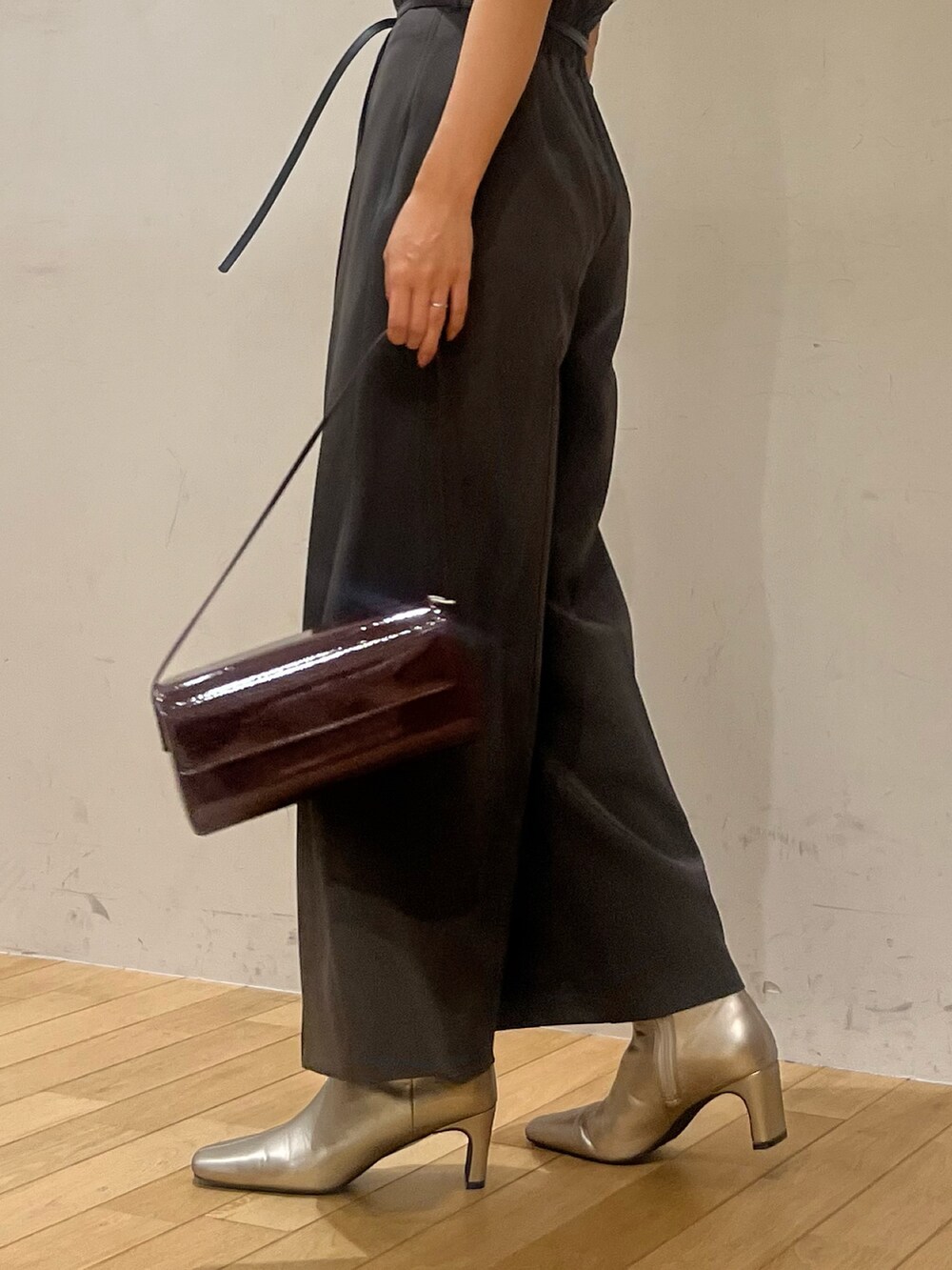 レッド系のショルダーバッグ、ベージュ系のニット/セーター、シルバー系のブーツを着用したレディースの秋コーディネートの6枚目の写真