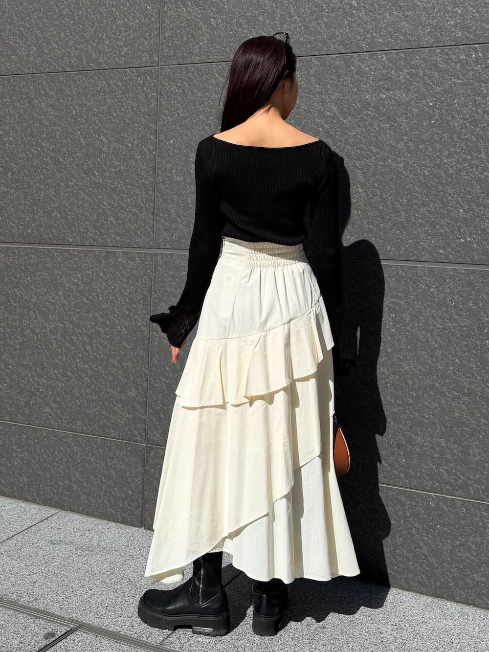 ホワイト系のスカート、ブラック系のニット/セーター、ブラウン系のハンドバッグを着用したレディースの冬コーディネートの3枚目の写真